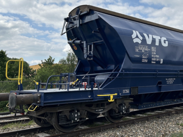 VTG-Hopperwagen auf einem Rangiergleis mit Lokomotive im Hintergrund.