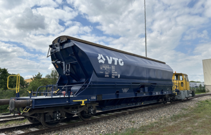 VTG-Hopperwagen auf einem Rangiergleis mit Lokomotive im Hintergrund.