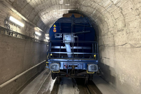 Hopperwagen durchfährt historischen Tunnel mit niedriger Deckenhöhe.